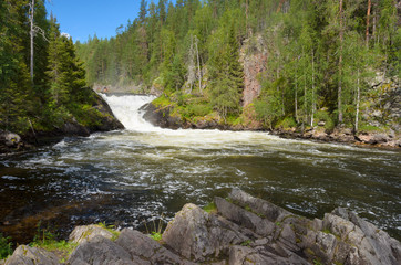 View from the river bank on waterfall in northern Finland in summer.