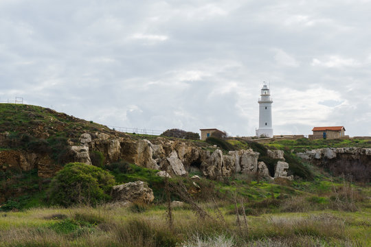 Photo of lighthouse on hill in background of cloudy sky