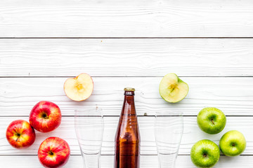 Apple cider. Low-alcoholic beveradge in dark bottle near beer glasses and fresh apples on white wooden background top view copy space