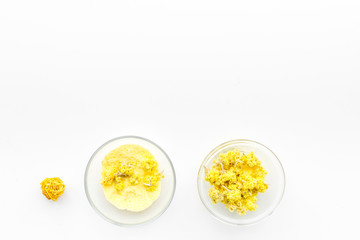 Aromatic spa salt. Yellow spa salt with delicate spring flowers on white background top view copy space