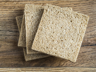Wholemeal bread without crust on wood background