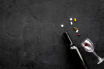 Alocohol abuse and alcoholism treatment concept. Glasses, bottles and medcine pills on black background top view copy space