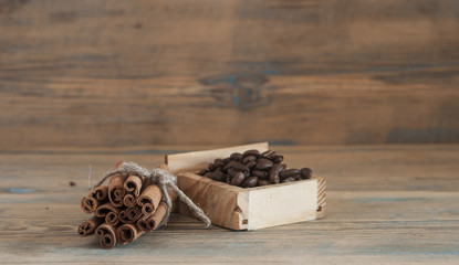 Pile of coffee beans, cinnamon sticks on old wood.
