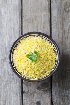 Couscous in bowl. Wooden background. Top view. Copy space.