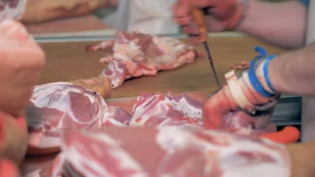 Worker is cutting pieces of fat off the meat.