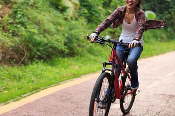 cheerful young woman cyclist cycling on forest trail