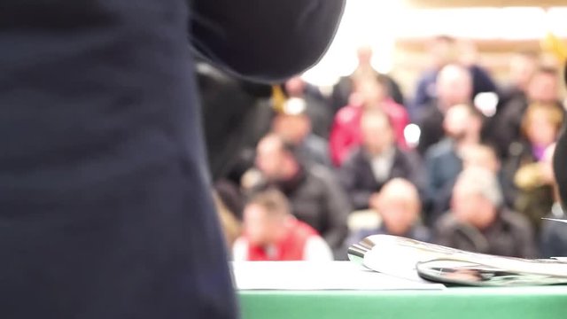 auctioneer of cattle in sale  banging the gavel on the table with unfocused audience in background , video hd 1920x1080	