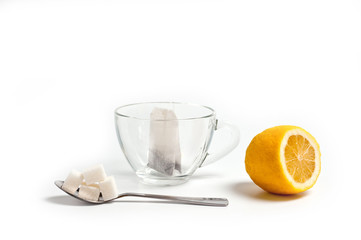 Glass cup for tea with a spoon, tea bag and lemon on a white background