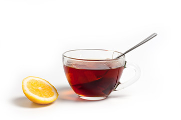 Glass cup for tea with a spoon, tea bag and lemon on a white background