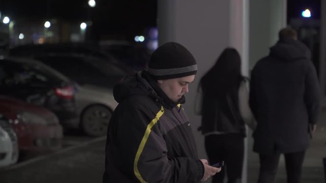 thick man uses a smartphone on the street