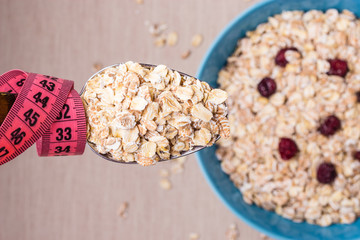 Oatmeal in bowl and measuring tape around spoon