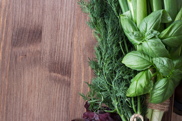Onions, basil dill on a wooden background.