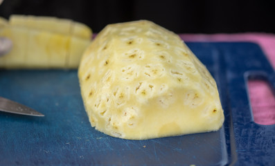 peeled pineapple on blue cut board
