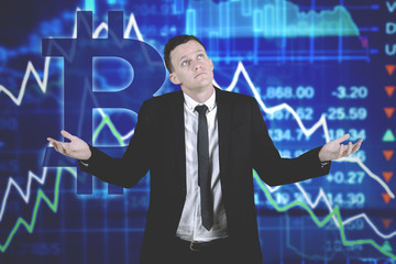 Confused caucasian businessman against declining bitcoin chart background