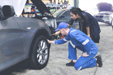 Caucasian mechanic helping a female client check on a tyre