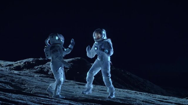 Male and Female Astronauts Wearing Space Suits Dance on the Surface of the Alien Planet. Humanity Colonizing Space Celebration Theme. Shot on RED EPIC-W 8K Helium Cinema Camera.