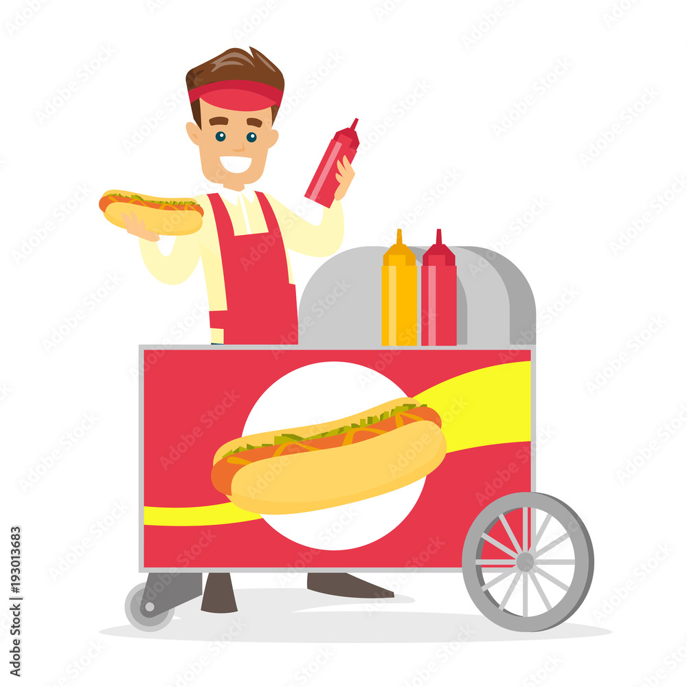 Canvas Prints young caucasian white street seller dressed in an apron standing with hot dog cart. small business a