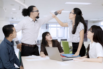Business people pointing at each other having an argument in a group meeting
