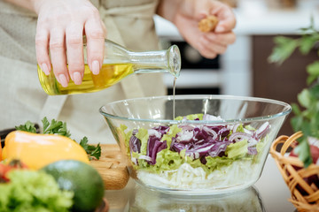 Obraz na płótnie Canvas Pouring olive oil on freshly made salad. 