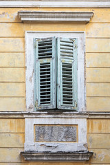 Fototapeta na wymiar Fenster mit grünem Fensterladen in einem gelben alten Haus
