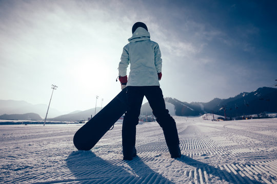 one snowboarder with snowboard looking at the snowobard piste in winter mountains