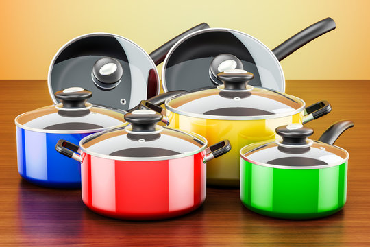 Set of colored cooking kitchen utensils and cookware. Pots and pans on the wooden table. 3D rendering