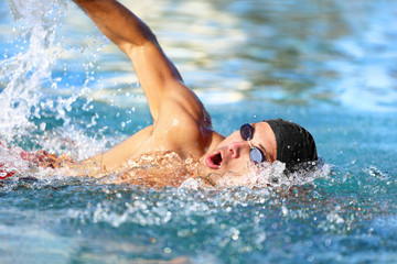 Man swimmer swimming crawl in blue ocean open water. Portrait of an athletic young male triathlete...