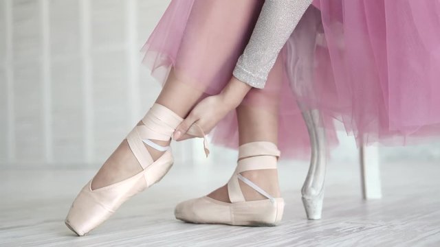 ballerina tying the pointes. ballet dancer wearing ballet shoes in the studio