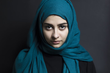 Portrait of a sad Arab girl in a hijab on a black background. Muslim woman with beautiful eyes. 
