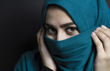 Portrait of a muslim girl in hijab with beautiful eyes on a black background.