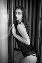 Young sexy woman in black lingerie standing in the doorway. Black and white photography