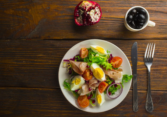 Fresh salad with mixed greens and cherry tomato in bowl on wooden background