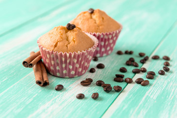 cupcakes with cinnamon sticks and coffee beans on a green wooden background