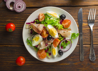 Fresh salad with mixed greens and cherry tomato in bowl on wooden background