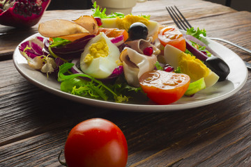 Fresh salad with mixed greens and cherry tomato in bowl on wooden background