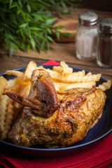 Roasted chicken with french fries on a plate.
