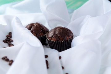 chocolate muffins with coffee beans on white fabric
