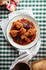Chicken legs cooked in italian cacciatore style with tomato sauce and fresh basil on green checkered table-cloth