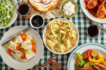 Traditional italian tuscan family dinner with homemade pasta and chicken cacciatore, focaccia and salad served on a table covered with green checkered tablecloth