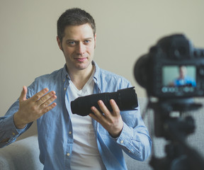 Handsome man making video blog about photo camera lenses.