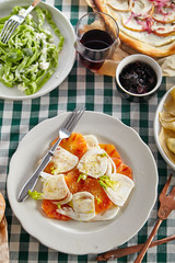 Traditional italian tuscan family dinner with homemade pasta and chicken cacciatore, focaccia and salad served on a table covered with green checkered tablecloth