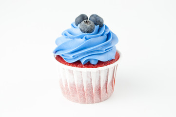 Cupcake red velvet with blue whipped cream decorated with blueberry on white background. Picture for a menu or a confectionery catalog.