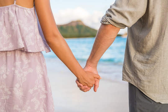 Honeymoon travel beach vacation couple holding hands in sunset. Newlyweds in love. Waikiki beach in Honolulu, Hawaii.