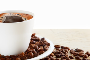 A cup of hot coffee with coffee beans on a white background