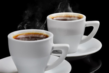 Two cups of hot coffee with steam on a black background