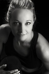 Naklejka premium Beautiful fit and healthy blond woman portrait in black top with knee drawn up artistic conversion