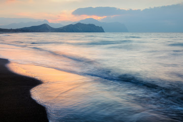 Picturesque seascape on beauty seacost. Sandy beach and blurred waves glowing by sunrice light. Vacations travel concept