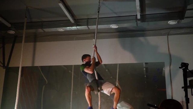 the athlete climbs the rope in the gym.Slow motion