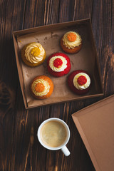 Box of colorful cupcakes and a cup of coffee