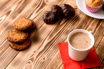 Cup of coffee and candy on wooden burnt background